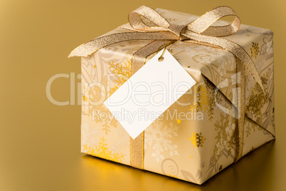 Christmas present with gold ribbon and blank tag