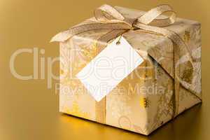 Christmas present with gold ribbon and blank tag