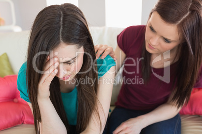 Girl comforting her crying friend on the couch