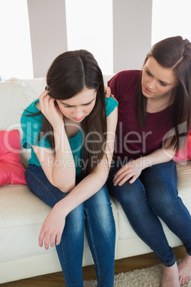 Girl comforting her upset crying friend on the couch