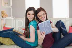 Girl showing her friend her tablet pc on the sofa