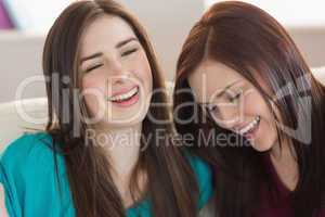 Two laughing friends sitting on the couch