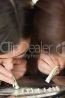 Two girls snorting an illegal white substance