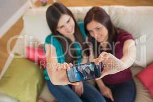 Two friends on the couch taking a selfie with smartphone