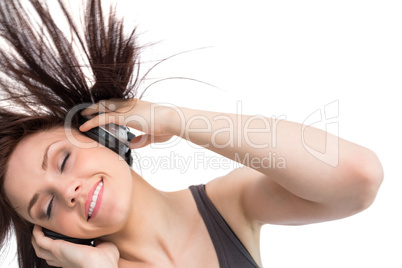 Smiling pretty brunette tossing her hair while listening to musi