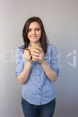 Cheerful pretty brunette holding cup of coffee