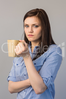 Serious pretty brunette holding cup of coffee