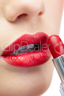 Extreme close up on glamorous model applying red lipstick