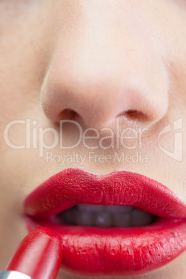 Extreme close up on sensual red lips being made up