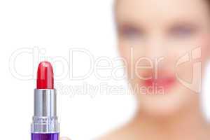 Nude blonde model holding red lipstick on foreground