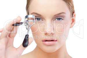 Pretty blonde model using eyelash curler