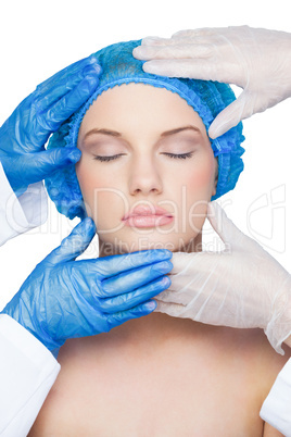 Surgeons examining peaceful young blonde wearing blue surgical c