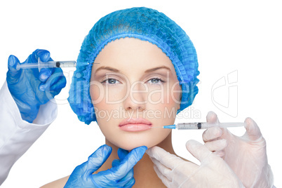 Surgeons making injection on calm blonde wearing blue surgical c