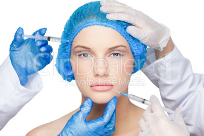 Surgeons making injection on pretty blonde wearing blue surgical