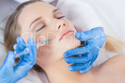 Surgeon making injection above lips on woman lying