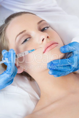 Surgeon making injection above lips on pretty woman lying