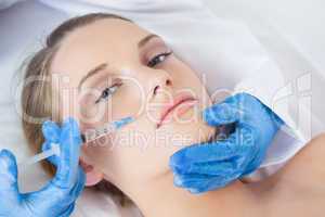 Surgeon making injection above lips on cute woman lying