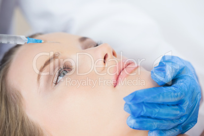 Surgeon making injection on forehead on calm woman lying