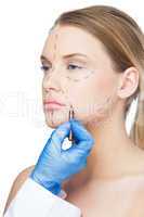 Surgeon drawing dotted lines on patients face