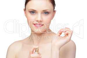 Smiling nude model spraying perfume on her wrist