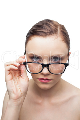 Unsmiling clean model looking over her classy glasses
