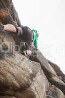 Determined man climbing a large rock face and seeing the summit