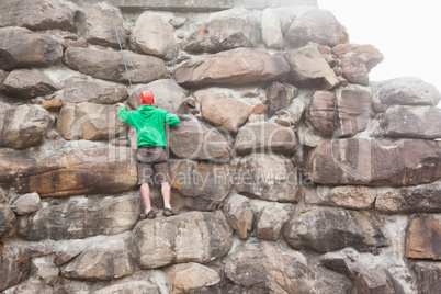 Determined man scaling a large rock face