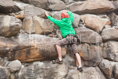 Determined man scaling a huge rock face