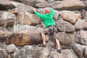 Determined man scaling a huge rock face