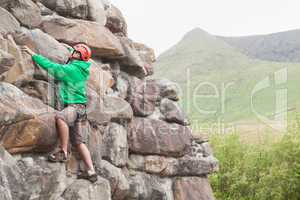 Focused man climbing a large rock face