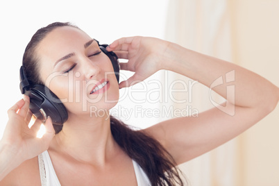 Relaxed brunette sitting on bed listening to music