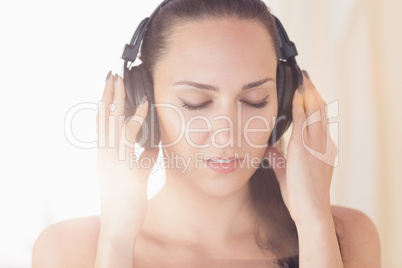 Pretty brunette sitting on bed listening to music