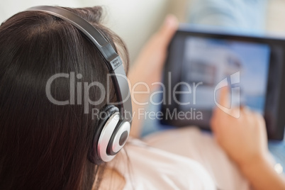 Girl using her tablet on the sofa and listening to music