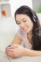 Relaxing asian girl lying on the sofa and listening to music wit