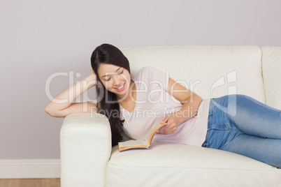 Pretty asian girl lying on the sofa reading book Pretty asian girl lying on the sofa reading book