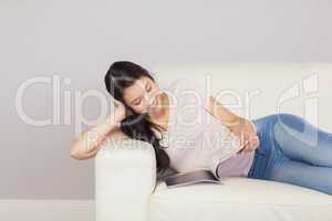 Pretty asian girl lying on the sofa reading a magazine