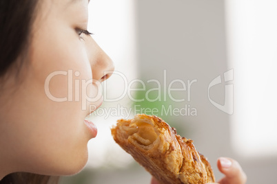 Young asian woman eating a pastry