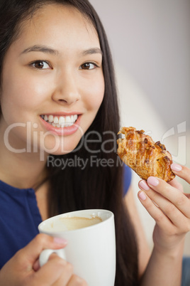 Young asian woman having a pastry with a cup of coffee