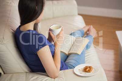 Young woman holding her coffee and reading book