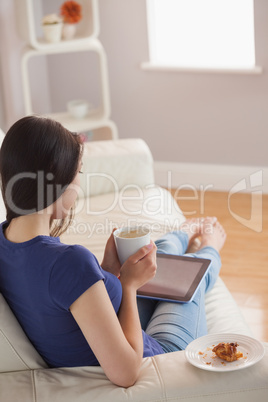 Young woman looking at tablet pc and holding cup of coffee
