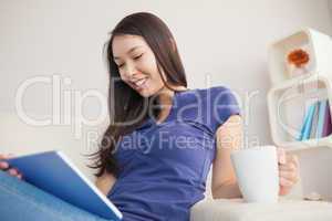 Young attractive asian woman using her tablet pc and holding mug