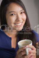Happy asian woman holding mug of coffee looking at camera