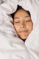 Young asian woman all wrapped up in her duvet