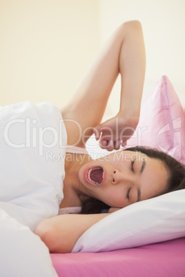 Young asian woman yawning and stretching in her bed