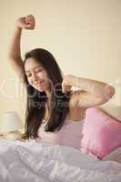 Young asian woman stretching in bed in the morning