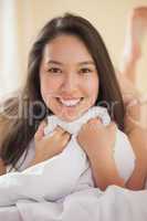 Cute young asian woman holding her duvet smiling at camera