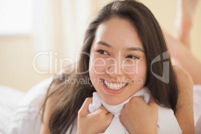 Cute young asian woman holding her duvet and smiling
