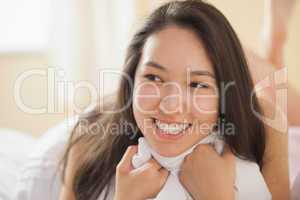 Cute young asian woman holding her duvet and smiling