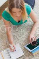 Woman lying on floor doing her homework using tablet