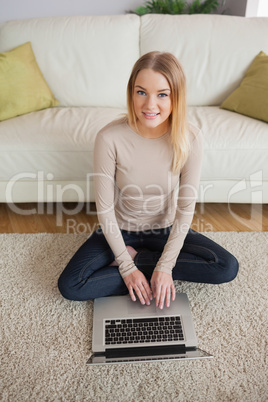 Happy woman sitting on floor using laptop